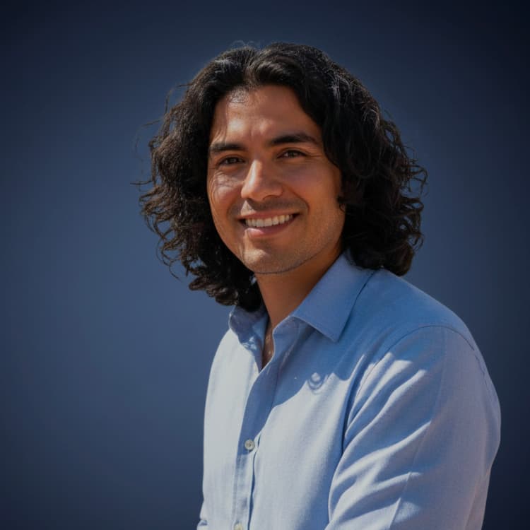 Smiling man with shoulder-length curly hair in a pale blue shirt